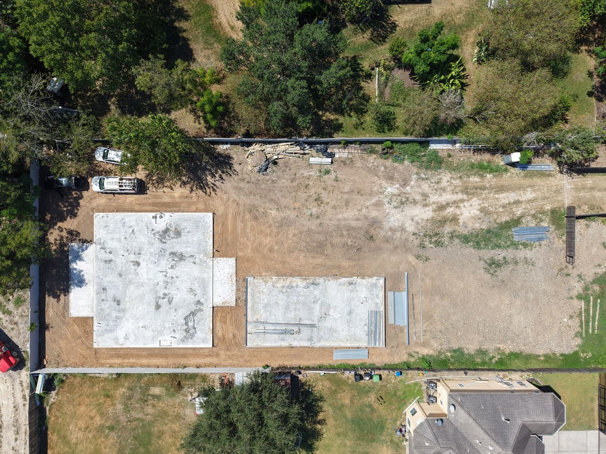 Aerial view of two new foundation slabs on a cleared lot