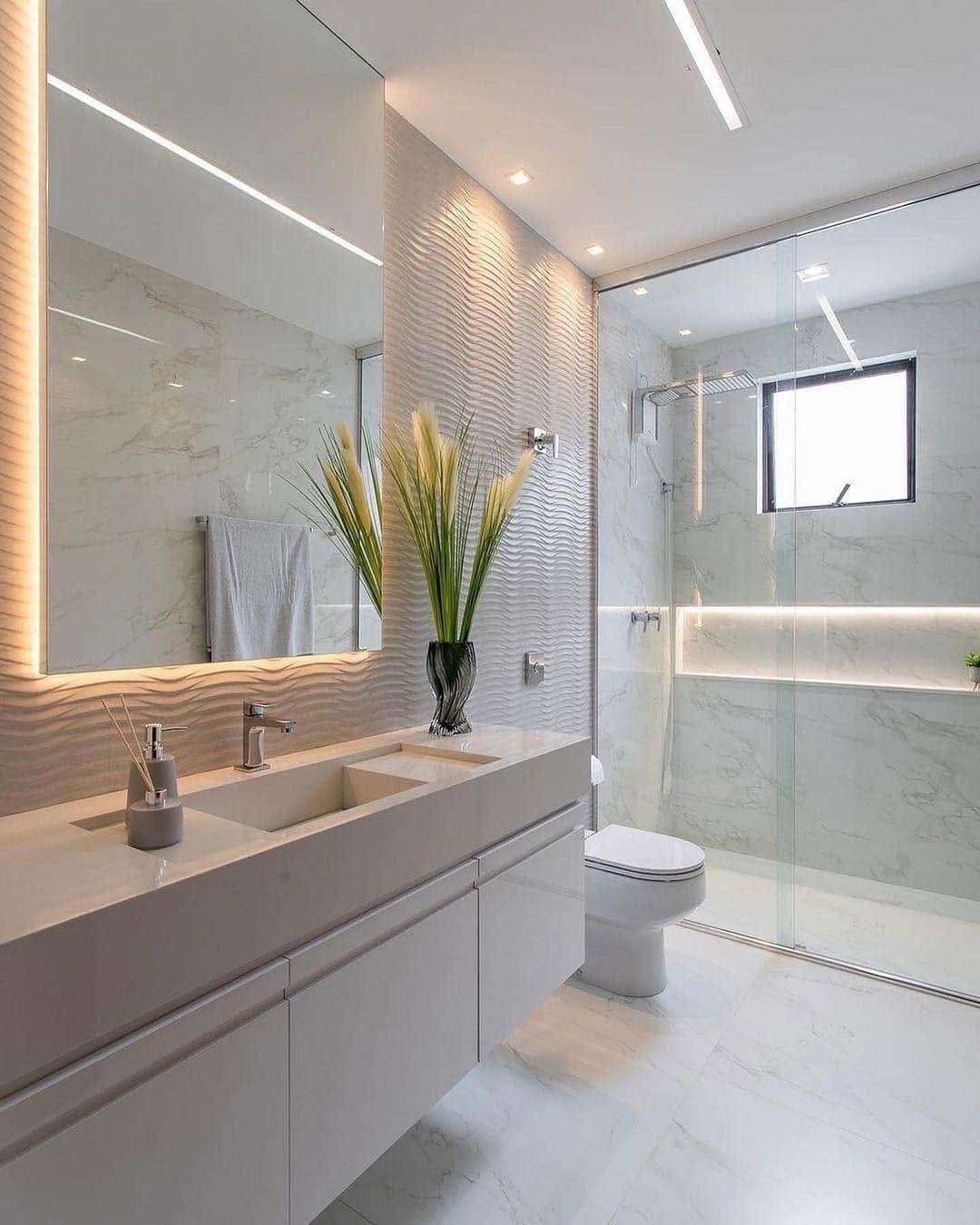 Bathroom with a floating vanity, backlit mirror and a glass walk-in shower