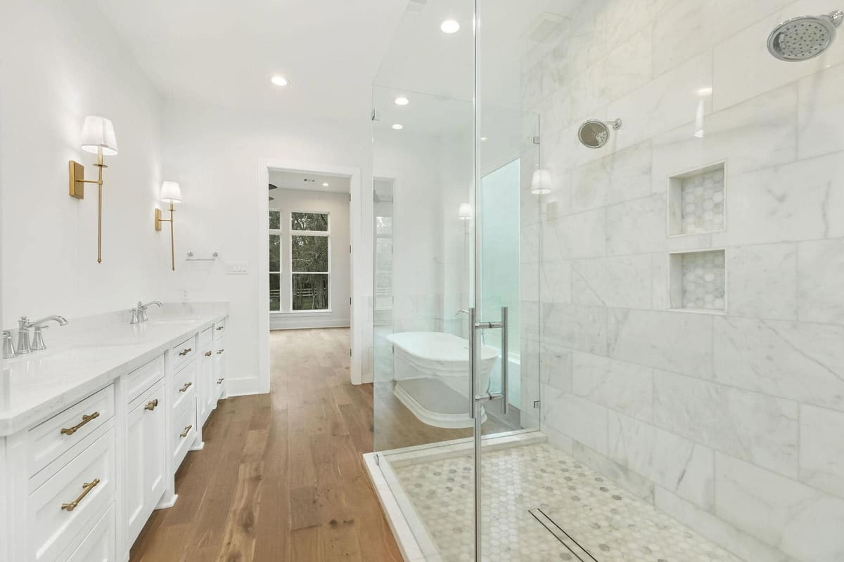 Primary bathroom with a frameless glass walk-in shower in marble tile and a long double vanity