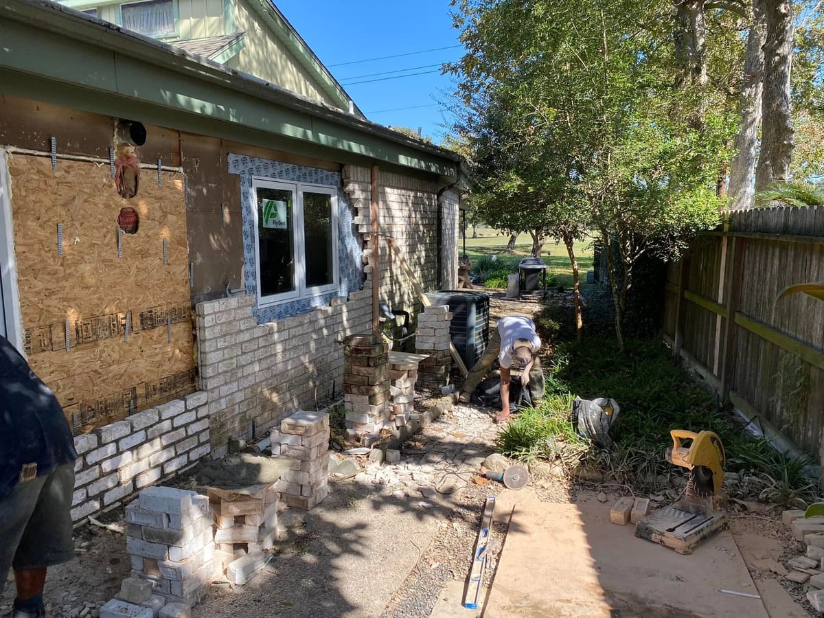 Crew removing old brick from an exterior wall during a renovation