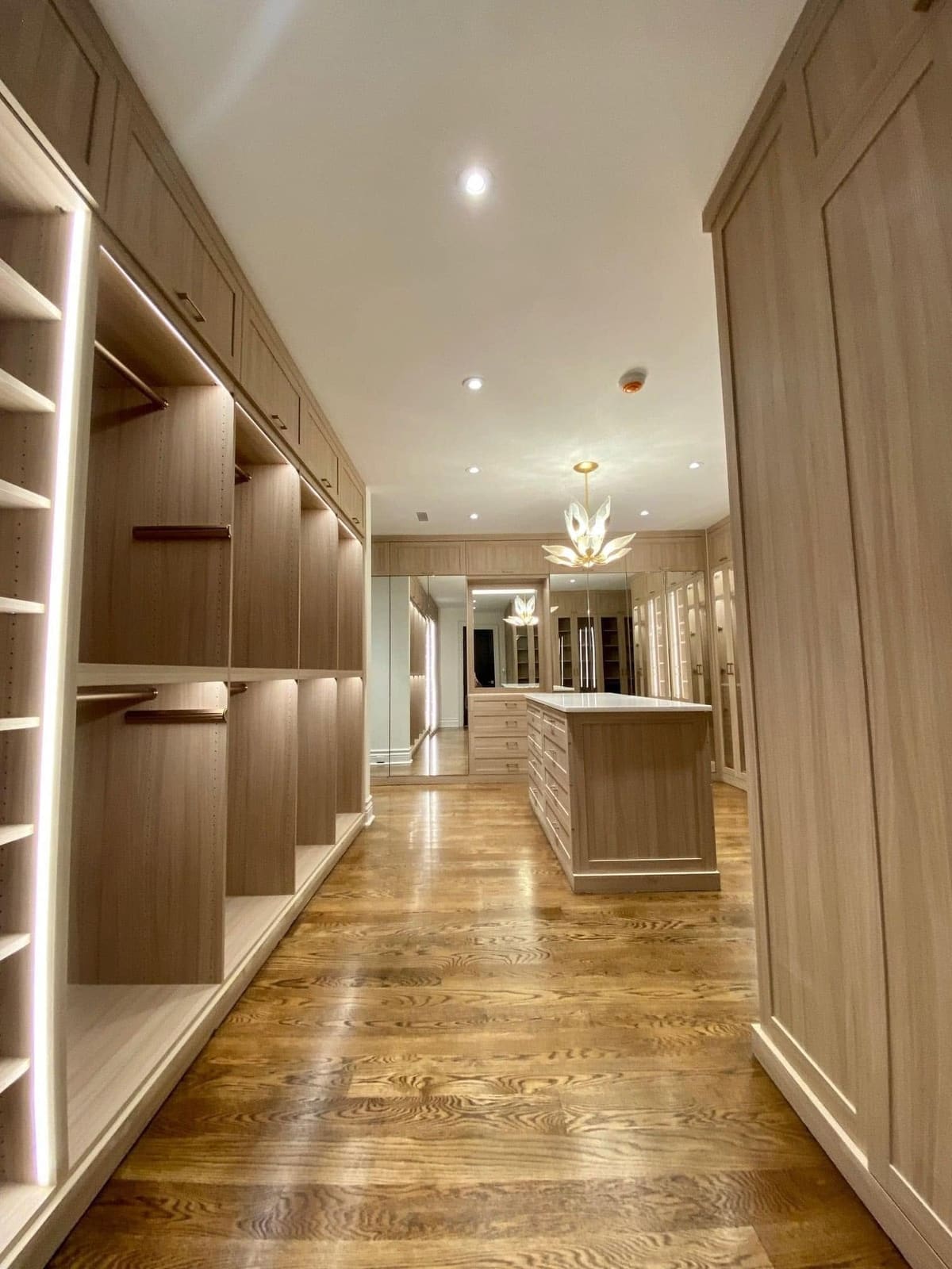 Walk-in closet with lit wood shelving and a center island