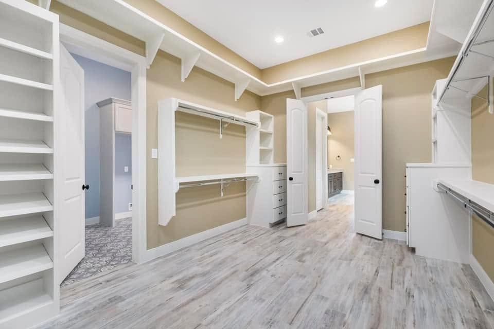 Walk-in closet with built-in shelving, hanging rods, drawers and cove lighting