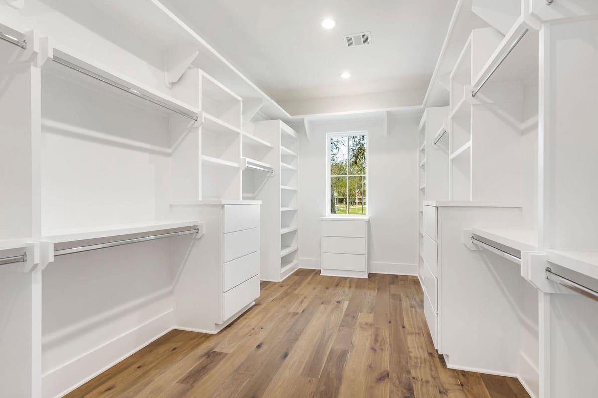Walk-in closet with white built-in shelving and wood floors