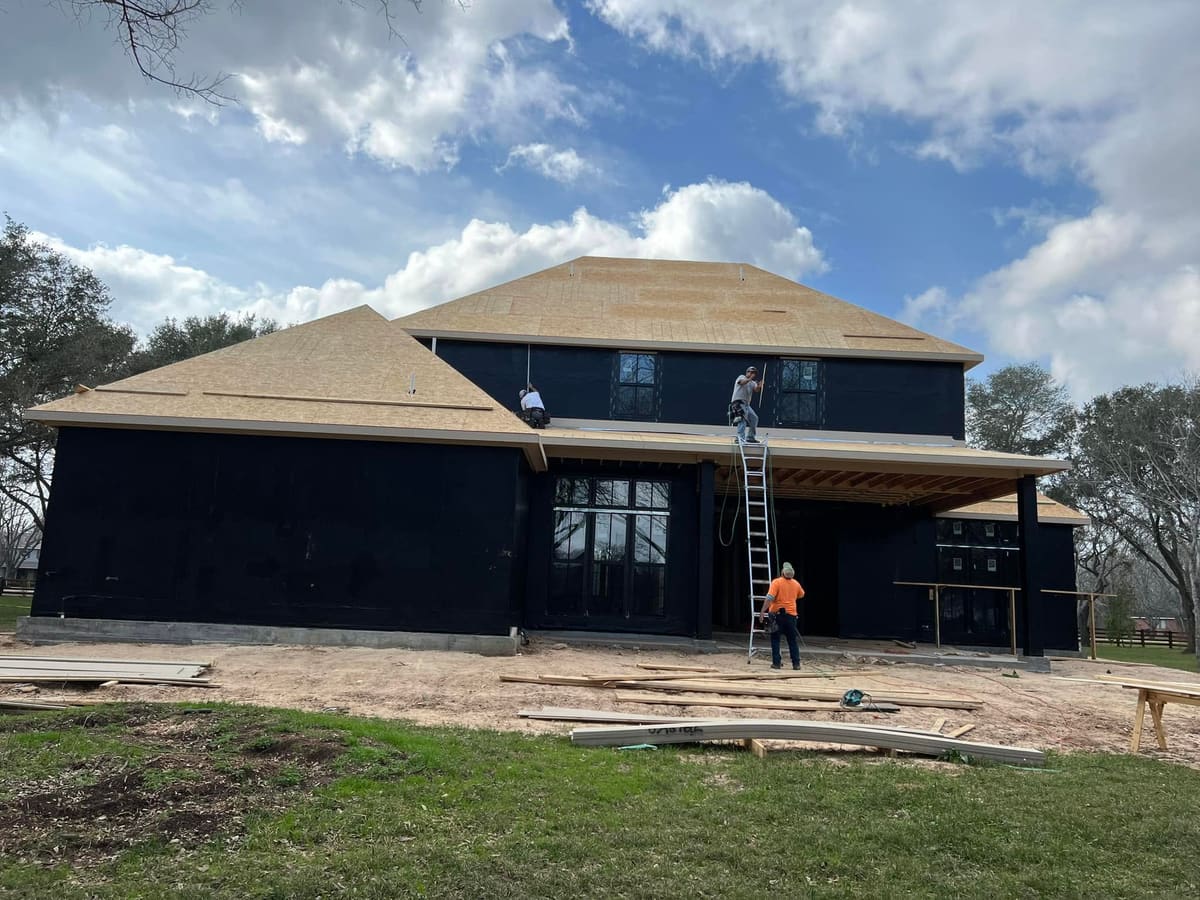 Roofing crew decking a two-story home under construction