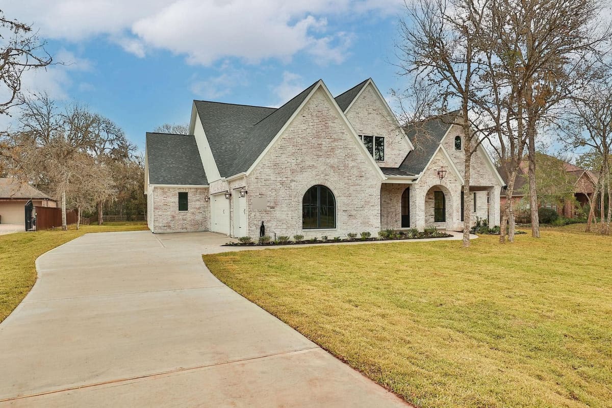 Front of a finished white-brick custom home with a three-car garage and new lawn
