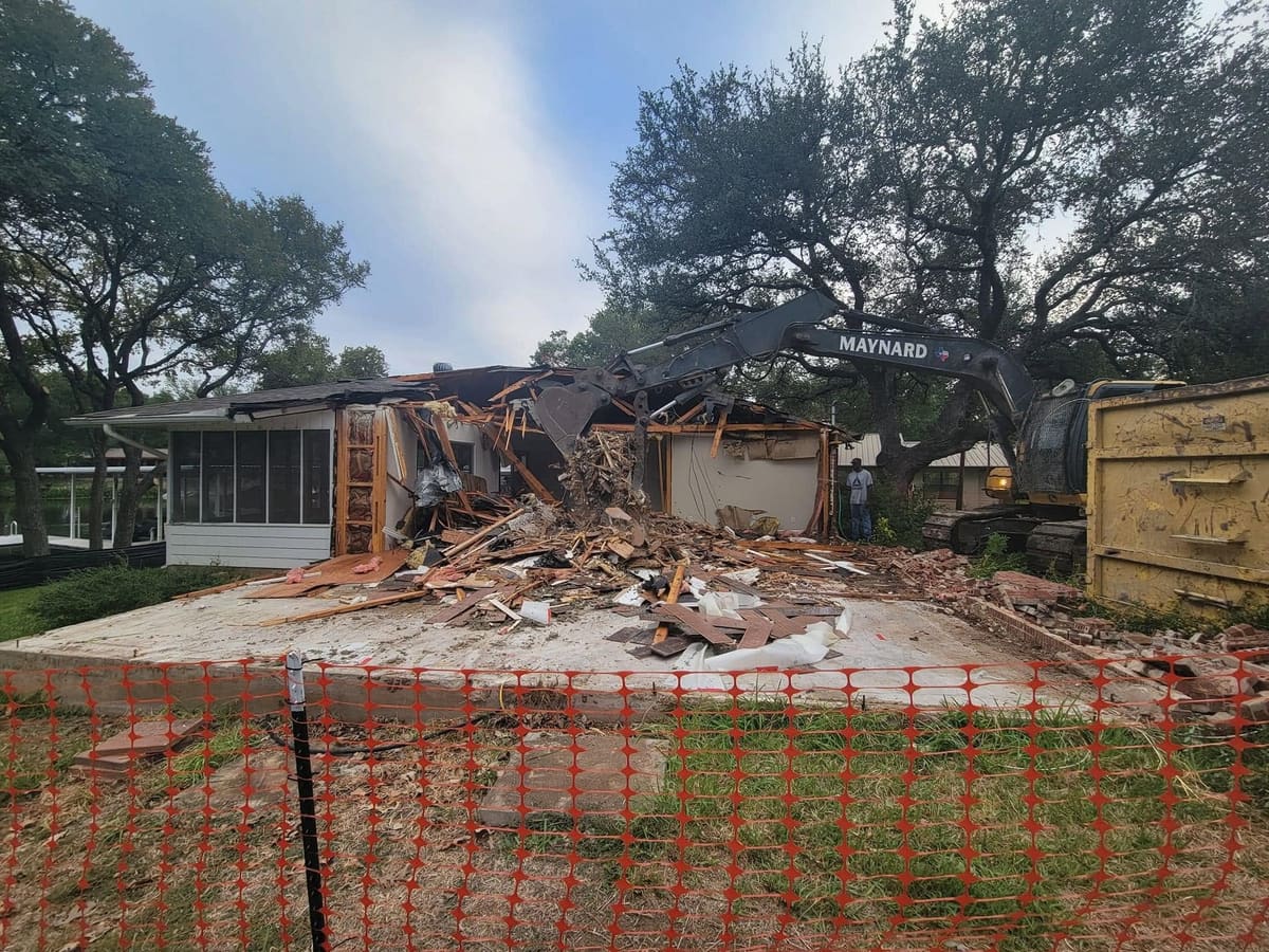 Excavator demolishing an older house to clear the lot for a new build