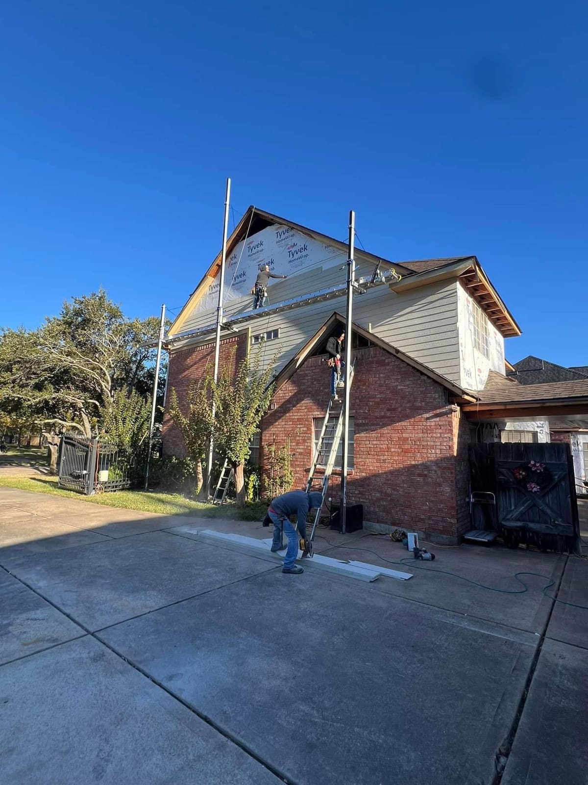 Two-story brick home with scaffolding during an exterior siding and roofing renovation
