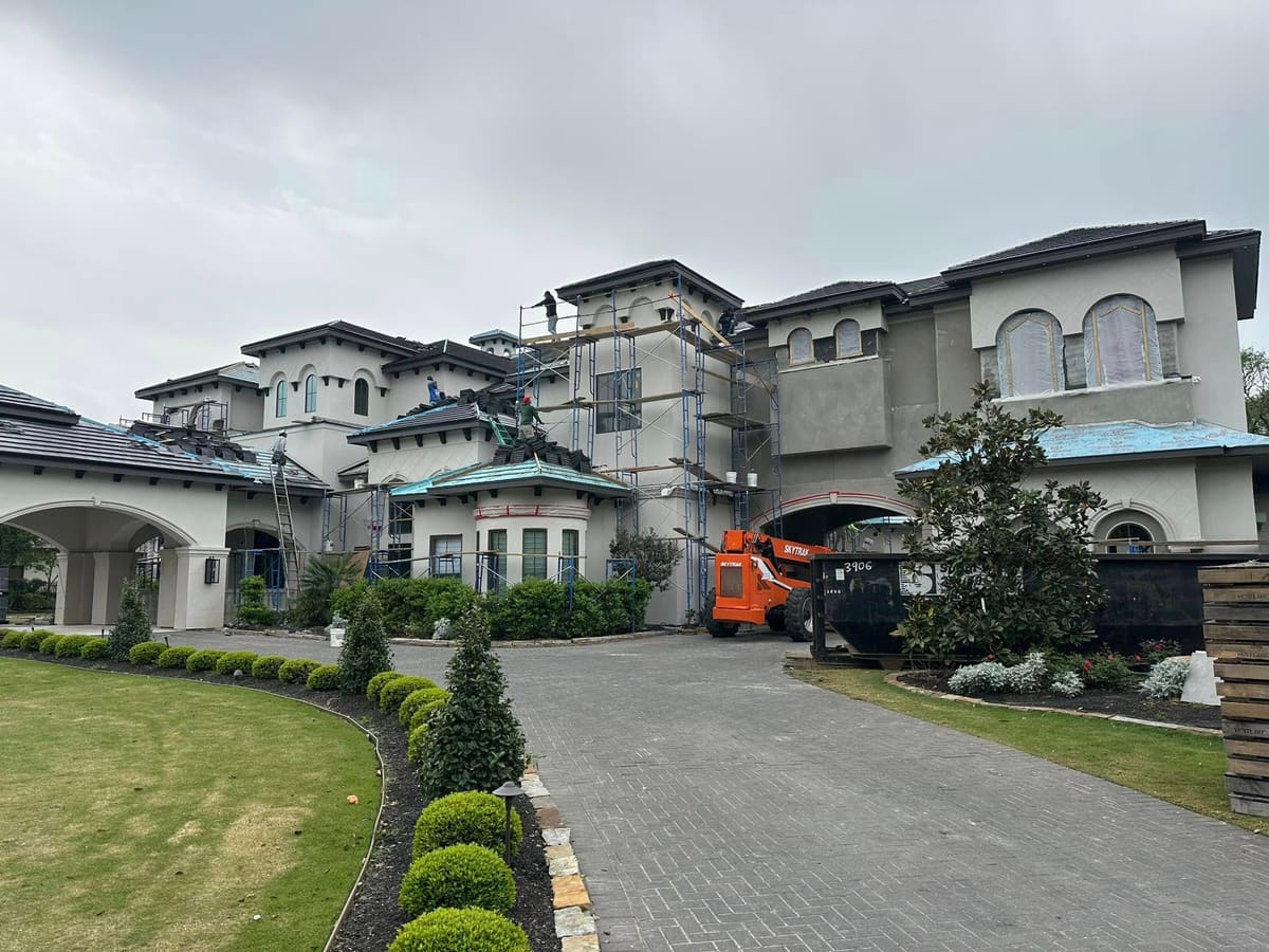 Large stucco home under exterior renovation with scaffolding