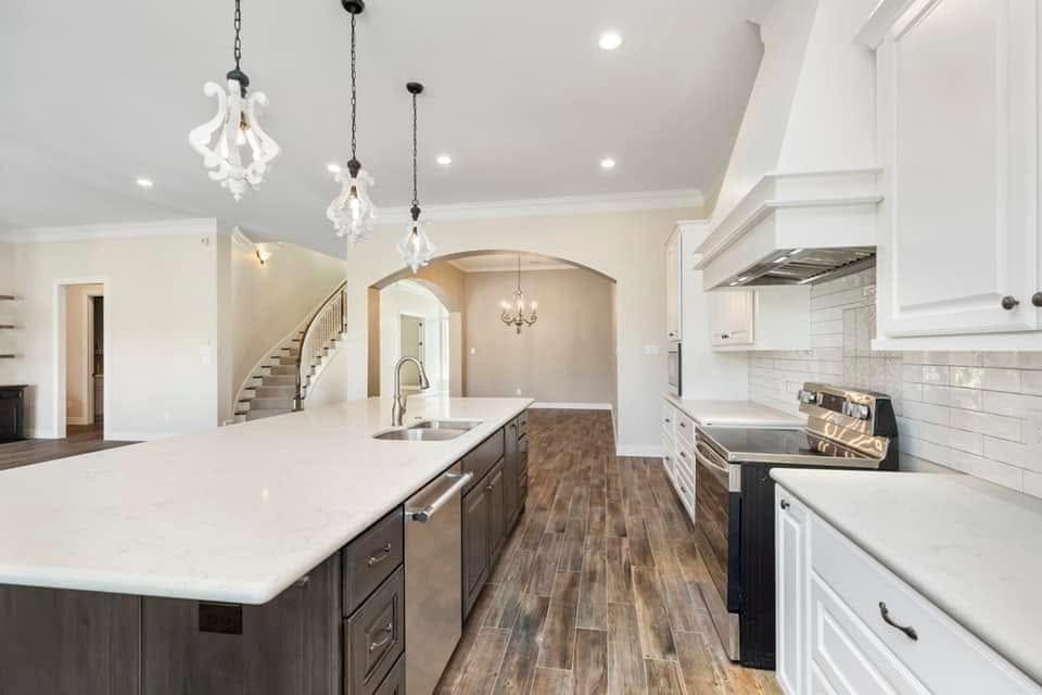 Kitchen with white perimeter cabinets, a dark island and a curved staircase beyond