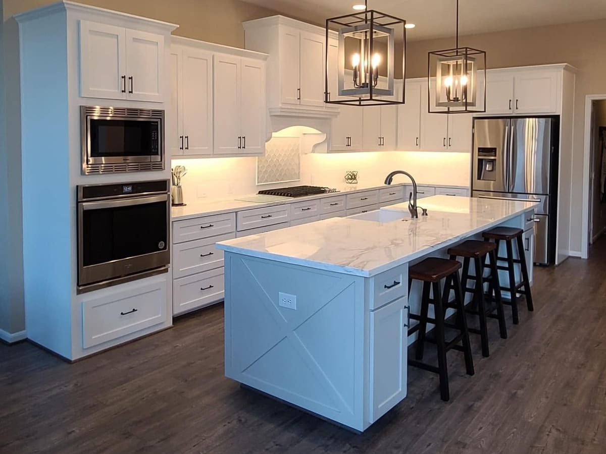 White kitchen with lantern pendants, stacked ovens and a large island with seating