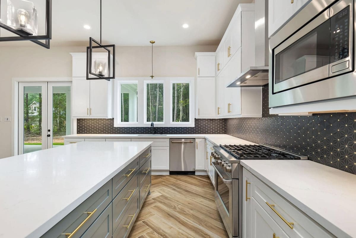 Kitchen with a quartz island, gas range, black geometric backsplash and gray lower cabinets