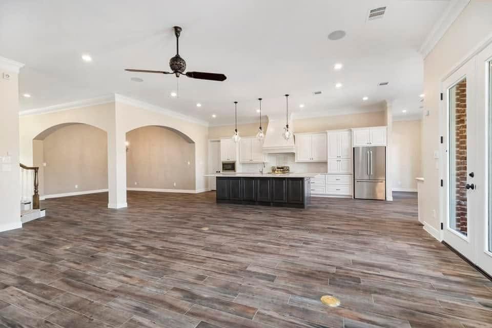 Open living area with arched openings, wood-look tile and a kitchen with a dark island