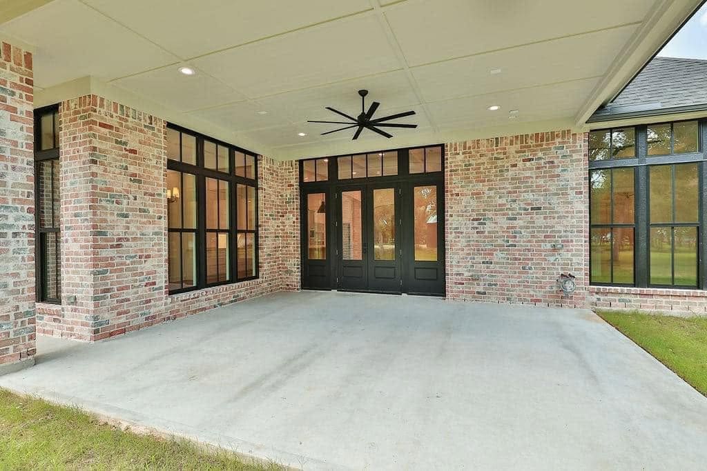 Covered patio tied into a brick home with black-framed windows and doors