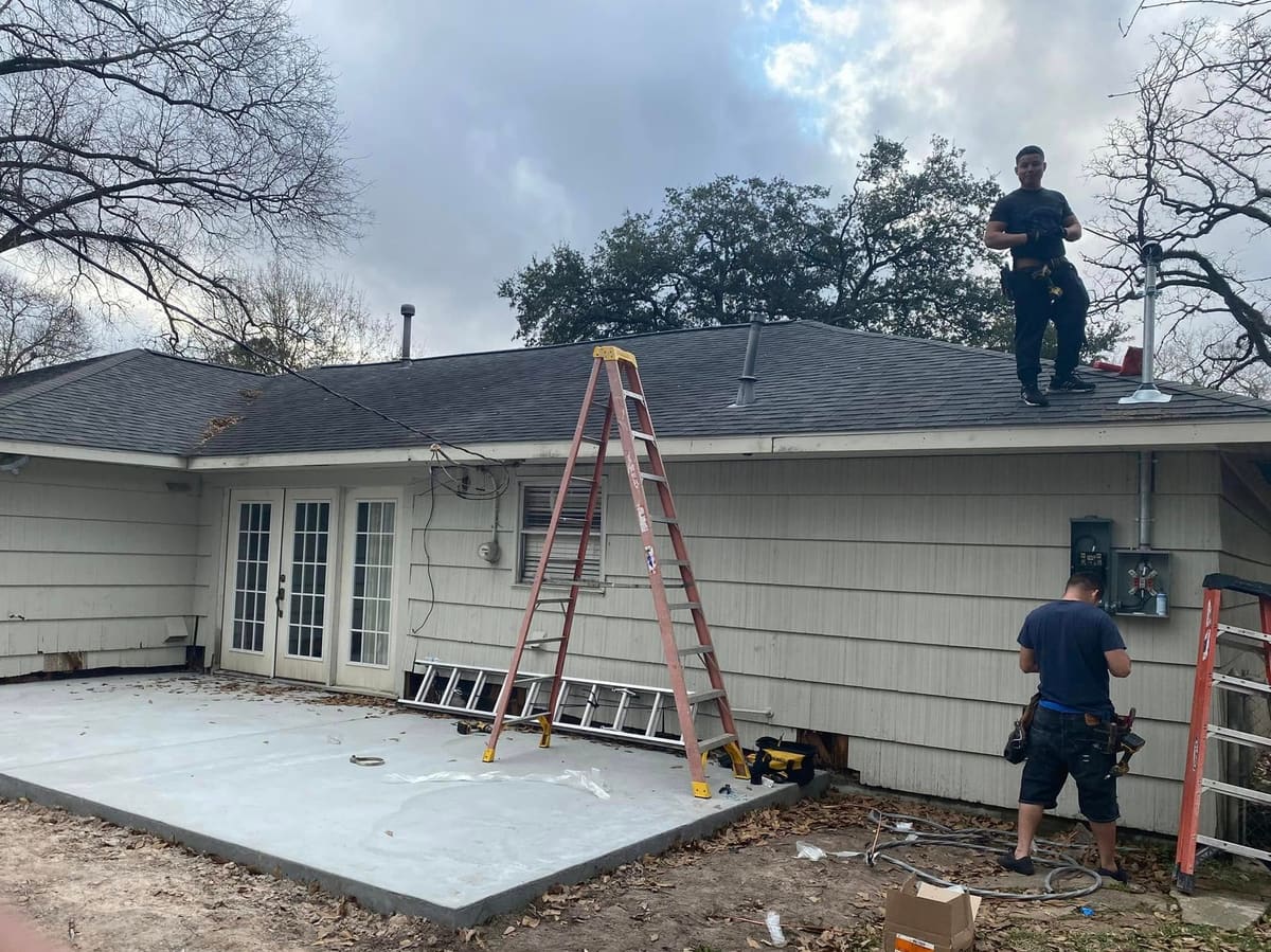 New concrete slab and crew at the back of a house before a patio cover is built