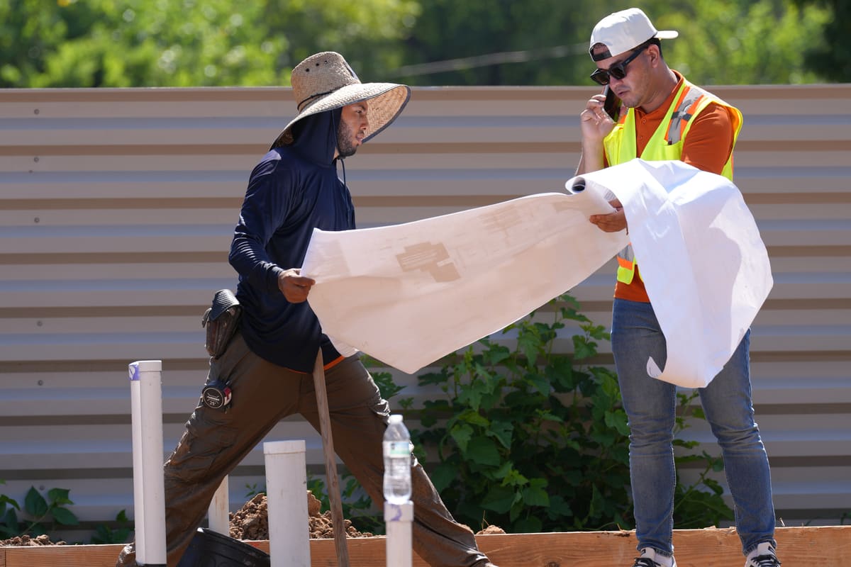 Two team members reviewing a drawing set on a home site