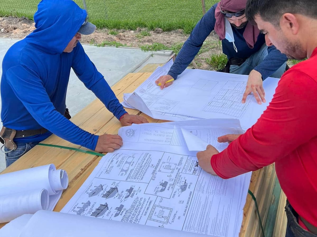 Crew members reviewing construction drawings on a job-site table