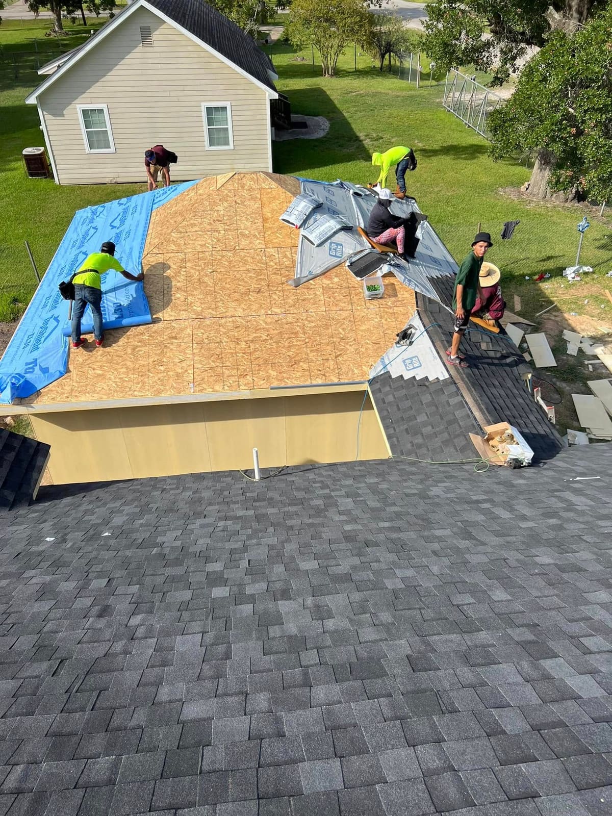 Roofing crew installing underlayment and shingles on a new roof