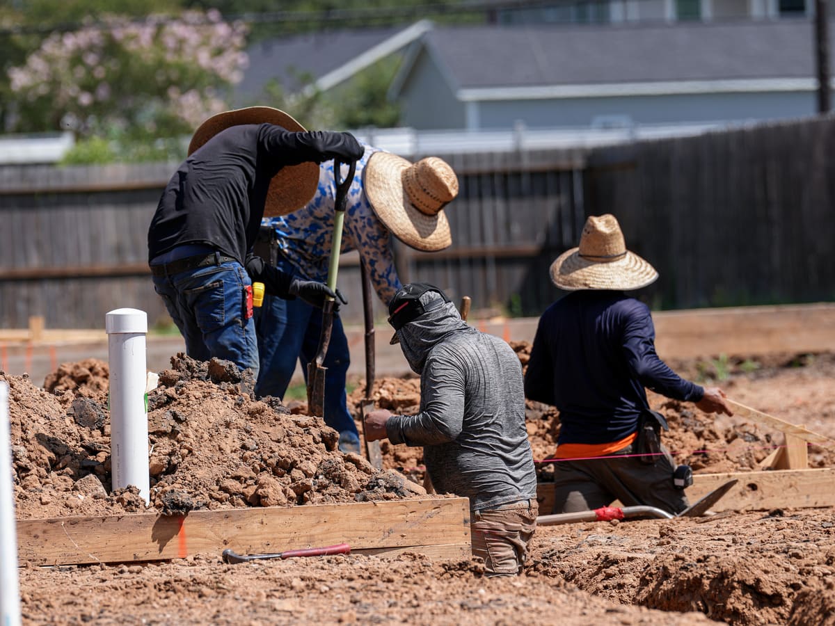 Crew digging plumbing trenches for a new foundation