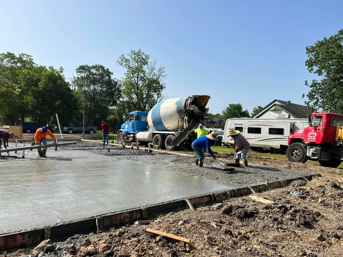 Crew placing concrete from mixer trucks for a new foundation slab