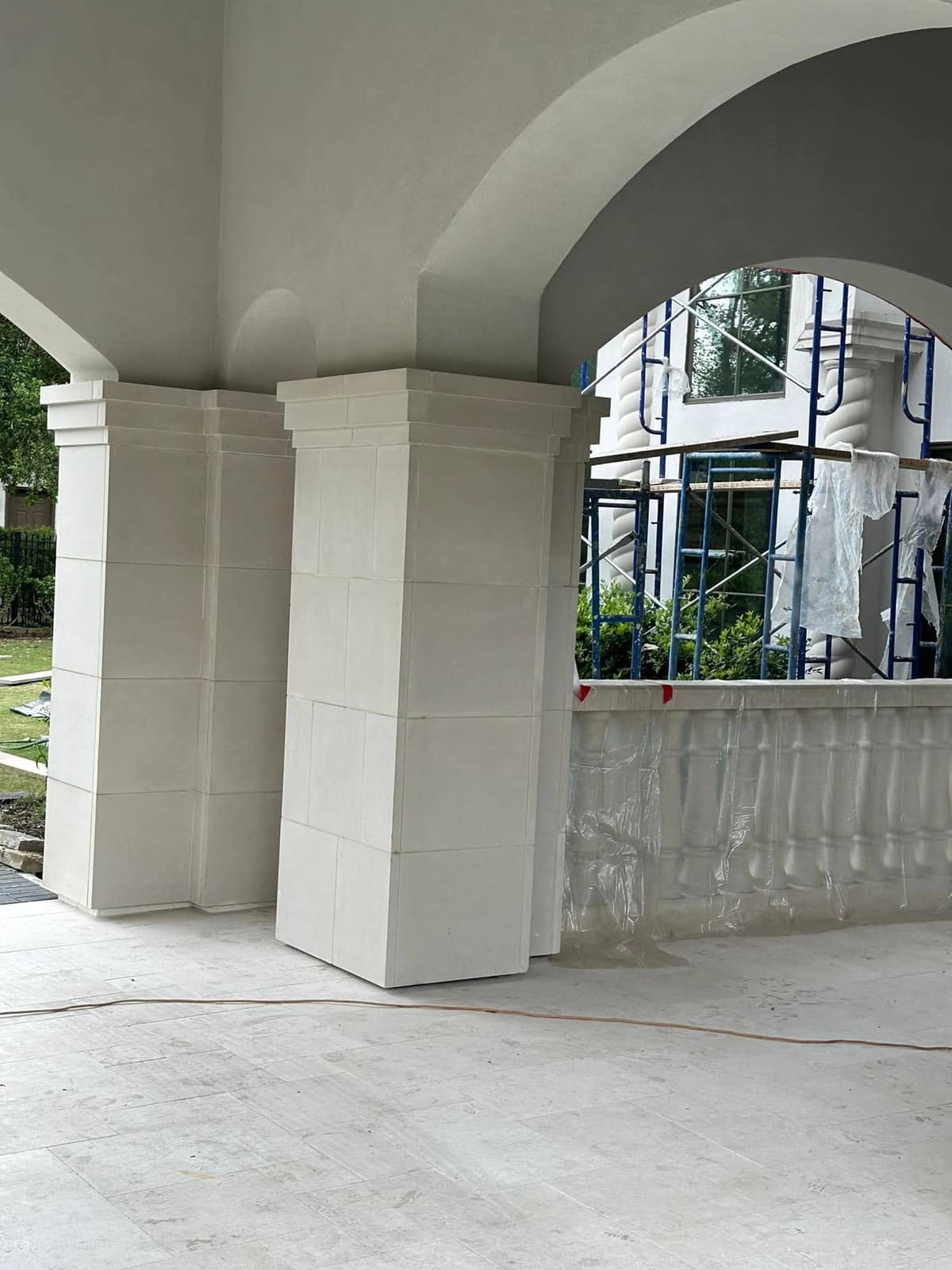 Covered porch with stucco arches, square columns and a balustrade during an exterior renovation