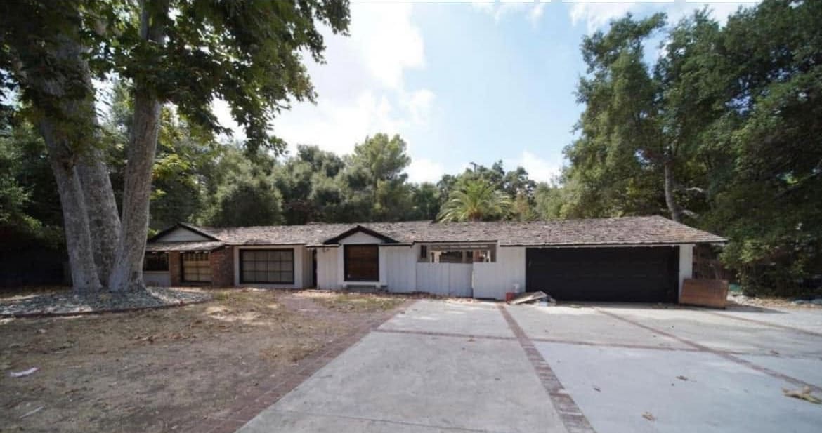 The original single-story house and driveway before a teardown and rebuild