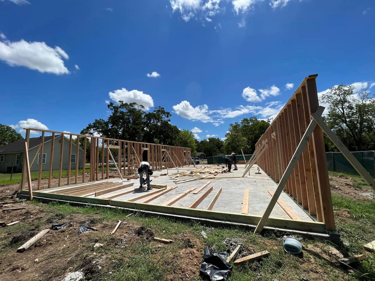 Crew raising framed walls on a new slab